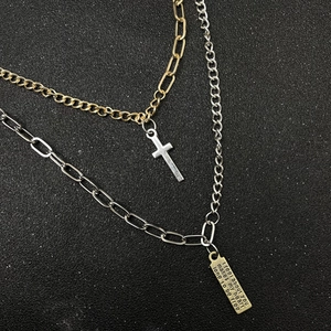 Double-layered gold and silver chain necklace with cross pendant and engraved rectangle tag