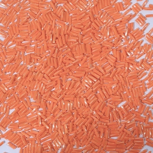 Macro shot of vibrant orange glass bugle beads for DIY jewelry and embroidery