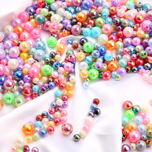 Dettaglio macro di perle acriliche AB colorate su raso bianco per creazioni artigianali DIY
