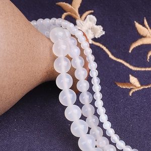 Gros plan de perles d'agate blanche translucides pour bijoux sur tissu bleu foncé