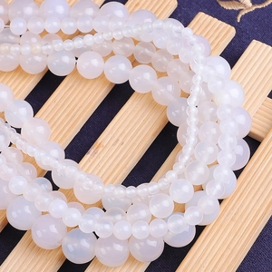 Détail macro de perles rondes en agate blanche translucide sur une clôture en bois