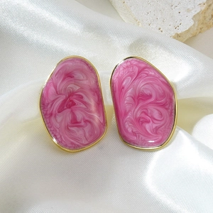 Boucles d'oreilles irrégulières en résine rose marbrée avec monture dorée sur du satin