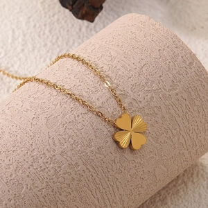 Close-up of golden four-leaf clover pendant with polished and radial texture finishes