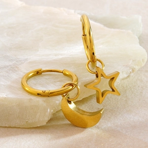 Detail of gold moon and star hoop earrings on a white stone background