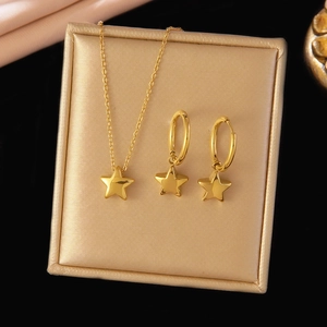 Detailed view of gold star jewelry set with necklace and hoop earrings on gold stand