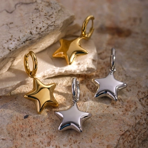 Vue macro de boucles d'oreilles étoiles dorées et argentées sur une texture de pierre