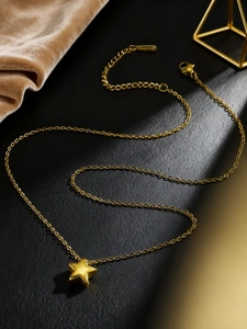 Close-up of gold star pendant necklace with O-chain and lobster clasp on black leather