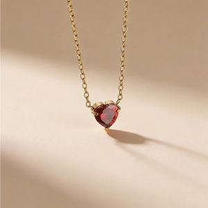 Detailaufnahme einer herzförmigen Kette mit rotem Edelstein und einer goldenen Kette