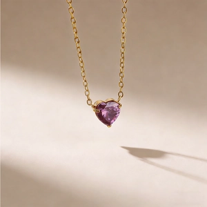 Makroaufnahme der goldenen Herz-Halskette mit violettem Geburtsstein in Krappenfassung