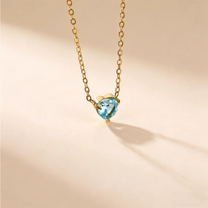 Makroaufnahme eines herzförmigen blauen Edelsteinanhängers an einer feinen Goldkette