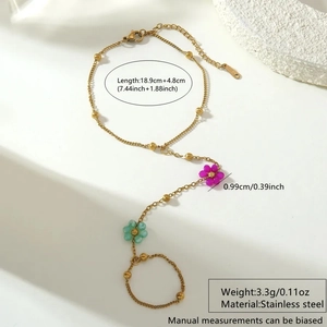 Detail of a gold stainless steel hand harness with beaded rose and mint flower charms