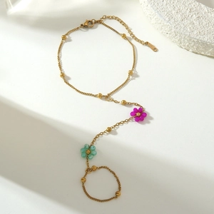 Detailed close-up of a golden stainless steel slave bracelet with colorful floral charms