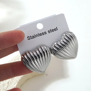 Gros plan de boucles d'oreilles cœur en argent avec rayures verticales sur carte