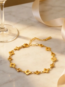 Nahaufnahme des goldenen Kleeblatt-Armbands auf Marmoroberfläche mit Sonnenlicht-Schatten