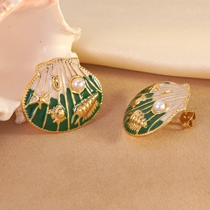 Detailed macro view of gold shell earrings with green enamel, starfish and pearl accents