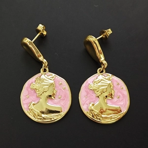 Detailed macro view of vintage gold-tone pink enamel earrings featuring a cameo profile design