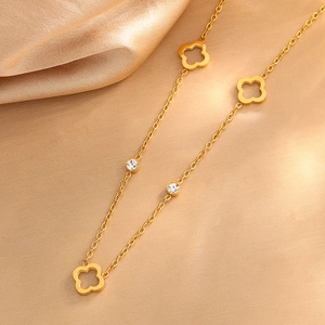 Golden hollow clover necklace with zircon stones on silk satin background