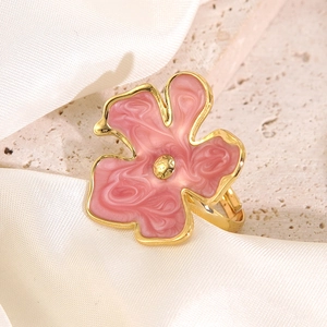 Macro detail of adjustable golden flower ring with pink enamel petals on stone texture