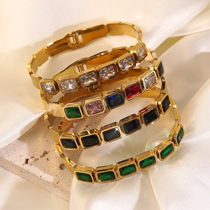 Close-up of stacked gold stainless steel bangles with colorful rectangular cut zircons