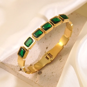 Macro detail of gold stainless steel bracelet with green rectangular cut zircons