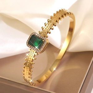 Vintage style gold open bangle with square green stone and intricate engravings