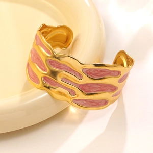 Vista macro bracciale placcato oro con smalto rosa e trama a onde su vassoio bianco