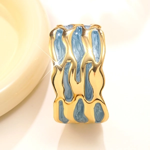 Dettaglio del bracciale dorato ondulato con intarsio in smalto marmorizzato celeste