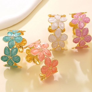 Dettaglio dei motivi floreali colorati in smalto su bracciali rigidi in acciaio dorato