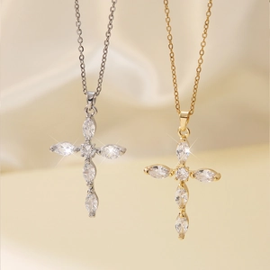 Elegant gold and silver cross necklaces with sparkling marquise zircons on beige fabric