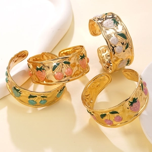 Dettaglio di bracciali dorati martellati decorati con motivi di frutta in smalto colorato