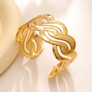 Dettaglio macro di un bracciale a fascia dorato lucido con motivo a onde intrecciate