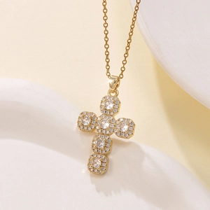 Macro shot of gold cross pendant with cluster-set cubic zirconia on stone base