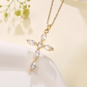 Detailed close-up of golden cross pendant with sparkling marquise-cut zircon stones