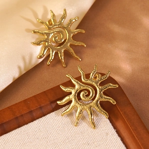 Macro detail of sunburst stud earrings featuring spiral patterns and hammered metal texture