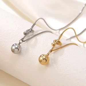 Close-up of gold and silver knot pendants with polished beads on snake chains