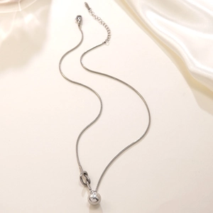 Detailed close-up of a silver knot snake chain necklace with a polished spherical pendant