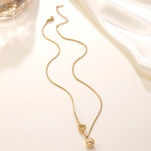 Detailed close-up of 18k gold plated snake chain necklace with knot and ball pendant
