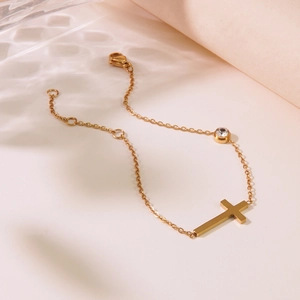 Elegantes Goldkreuz Armband mit Zirkonia und verstellbarer Kette auf stilvollem Wellen-Hintergrund