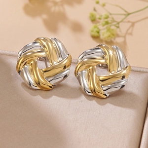 Detail van tweekleurige geometrische oorbellen op champagne fluweel met bloemen