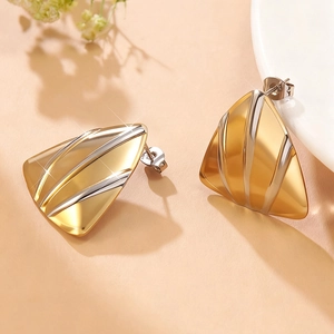 Detailopname van geometrische driehoekige oorbellen in tweekleurig goud en zilver