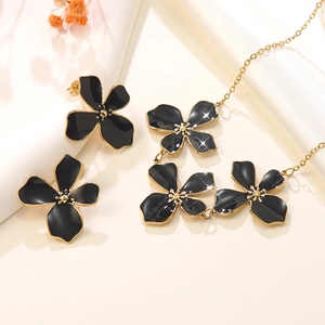 Schmuckset mit schwarzen Emaille-Blumen-Halskette und Ohrringen auf weißem Stoffhintergrund