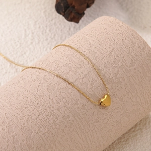 Polished 18k gold plated stainless steel heart pendant necklace for women on a pink pedestal