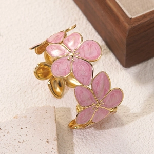 Detail eines goldenen Armreifs mit pinkfarbenen Emaille-Blüten und Marmorierung