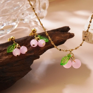 Sweet pink cherry jewelry set with necklace and earrings on a rustic wood stand