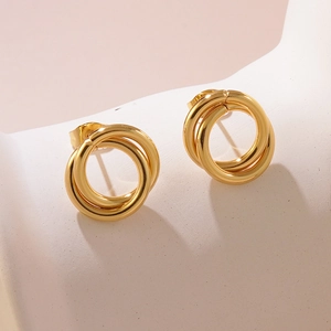 Detail of elegant gold double loop entwined stud earrings on white stone background