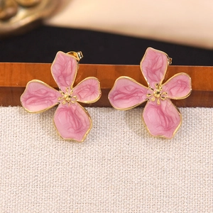Boucles d'oreilles fleurs en émail rose et bords dorés sur un support en bois