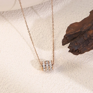 Macro detail of rose gold geometric cylinder pendant with inlaid zircon stones