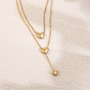 Detailed view of a gold double-layer necklace with three polished heart-shaped pendants