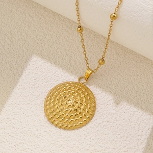 Detail of gold geometric round pendant with honeycomb texture and beaded chain link