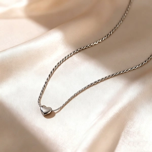 Poliertes Herzanhänger-Halskette aus Sterlingsilber auf elegantem champagner Seidenstoff